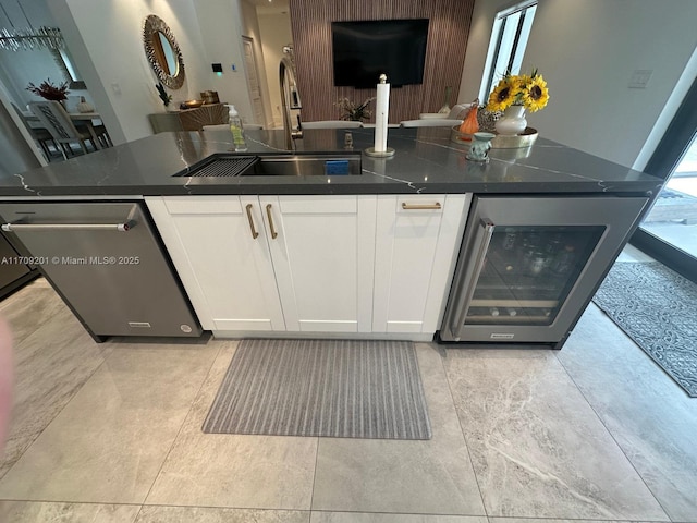 bar featuring white cabinets, sink, stainless steel dishwasher, and beverage cooler