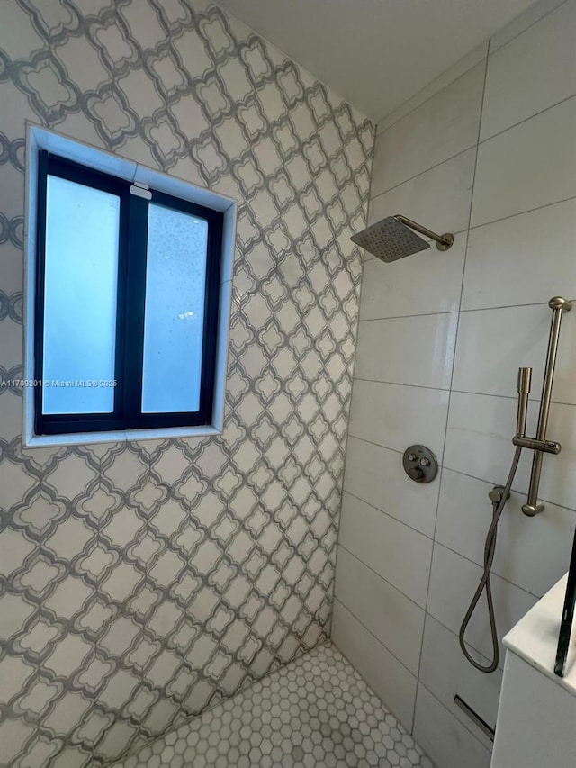 bathroom with tile patterned flooring, a tile shower, and vanity