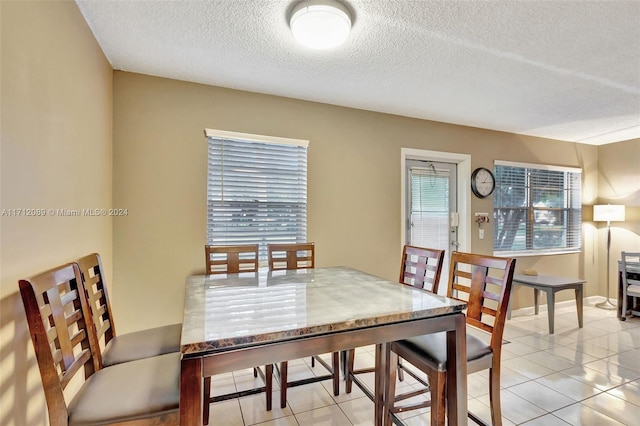 tiled dining room featuring a textured ceiling