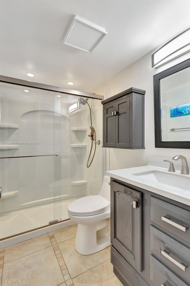 bathroom featuring tile patterned floors, vanity, a shower with shower door, and toilet