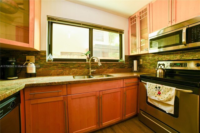 kitchen featuring dark wood-type flooring, sink, decorative backsplash, light stone countertops, and appliances with stainless steel finishes