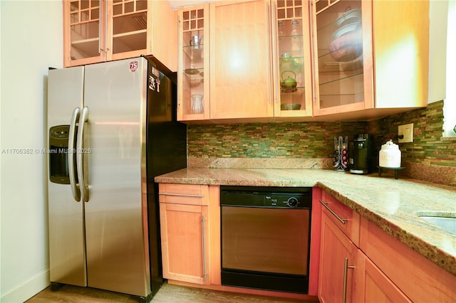 kitchen featuring light stone countertops, stainless steel refrigerator with ice dispenser, black dishwasher, and tasteful backsplash