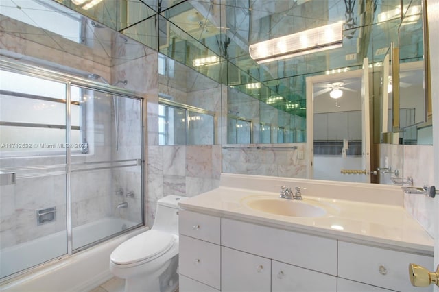 full bathroom with vanity, toilet, shower / bath combination with glass door, and tile walls