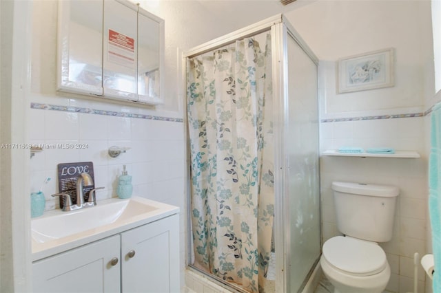 bathroom featuring a shower, vanity, tile walls, and toilet