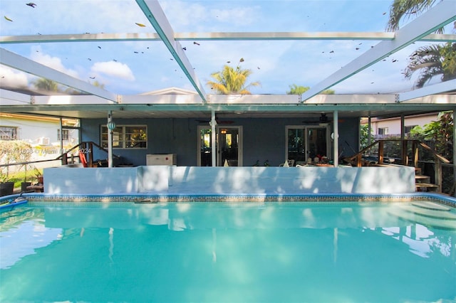 view of swimming pool with glass enclosure and ceiling fan