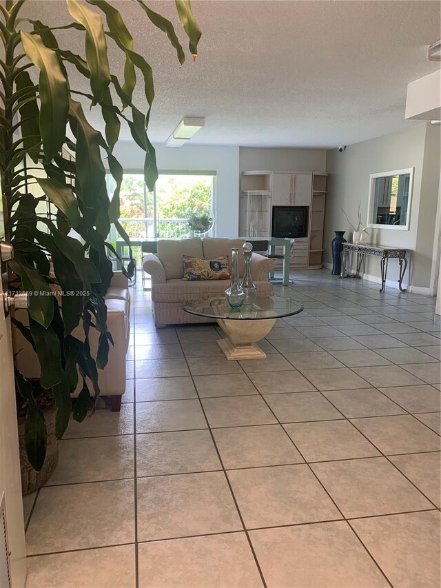 unfurnished living room featuring light tile patterned floors, baseboards, and a textured ceiling