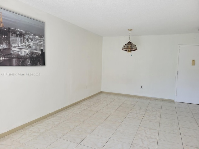 spare room featuring baseboards and a textured ceiling