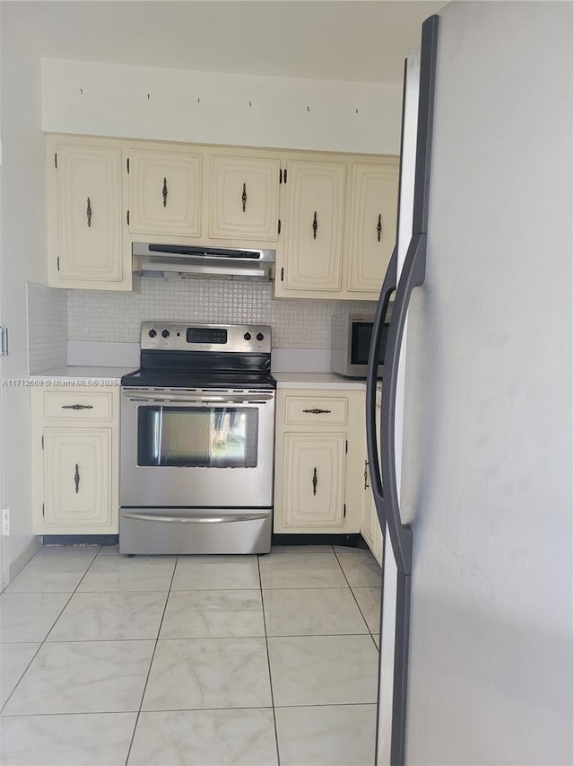 kitchen featuring light countertops, appliances with stainless steel finishes, cream cabinets, and under cabinet range hood