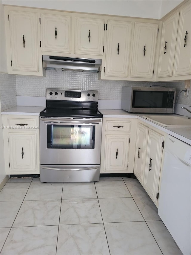 kitchen with tasteful backsplash, stainless steel appliances, light countertops, under cabinet range hood, and a sink