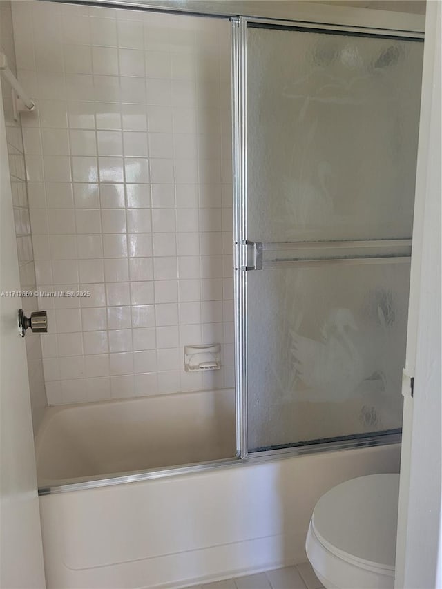 bathroom with toilet and bath / shower combo with glass door