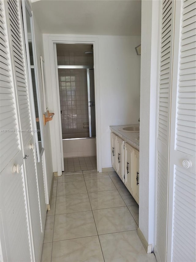 bathroom featuring enclosed tub / shower combo, vanity, baseboards, a closet, and tile patterned floors