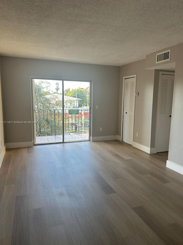 unfurnished room featuring dark wood-type flooring and a textured ceiling