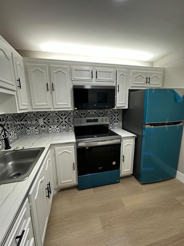 kitchen with sink, stainless steel electric range, refrigerator, white cabinets, and decorative backsplash