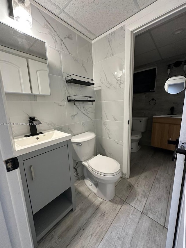 bathroom featuring vanity, a drop ceiling, and toilet