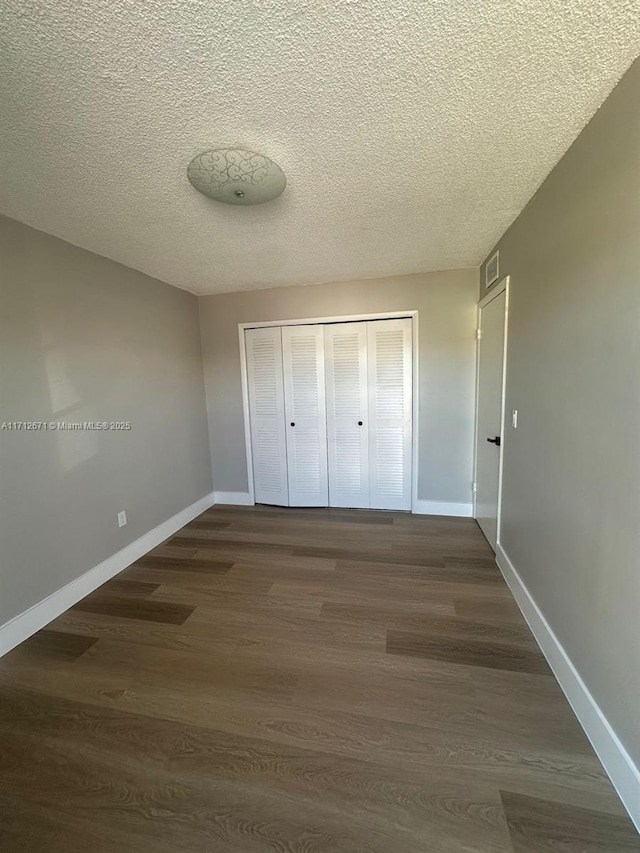 unfurnished bedroom with dark hardwood / wood-style floors, a closet, and a textured ceiling