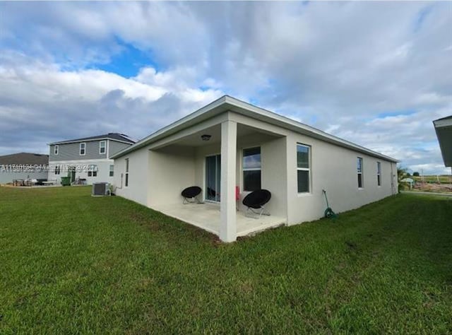 back of property with a patio, a yard, and central AC