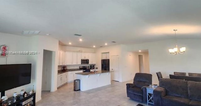 kitchen featuring a kitchen island, electric range, an inviting chandelier, white cabinetry, and hanging light fixtures