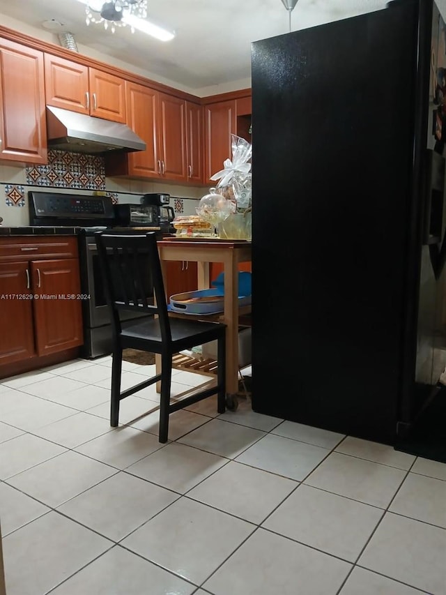 kitchen featuring backsplash, light tile patterned floors, and black appliances