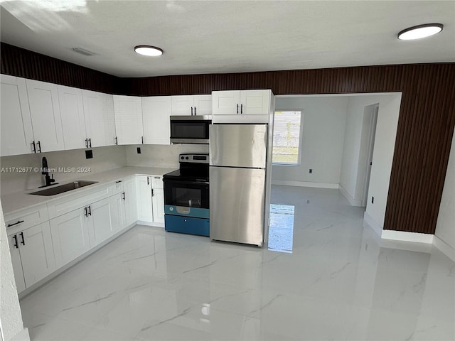 kitchen with white cabinets, a textured ceiling, stainless steel appliances, and sink