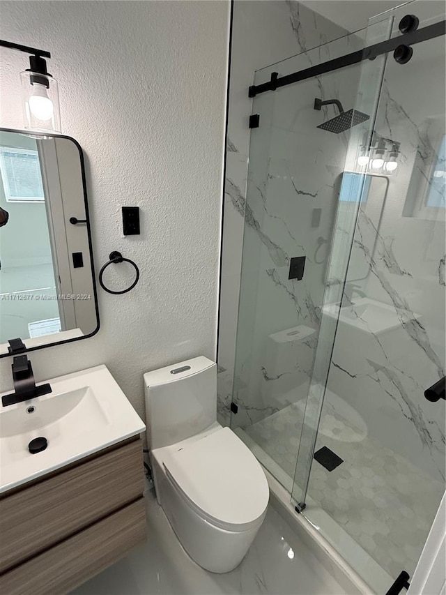 bathroom featuring a shower with door, vanity, and toilet