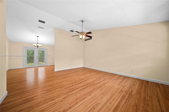 empty room featuring light wood-type flooring, a textured ceiling, visible vents, and vaulted ceiling