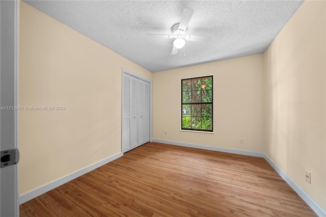 unfurnished bedroom featuring ceiling fan, light hardwood / wood-style floors, a textured ceiling, and a closet