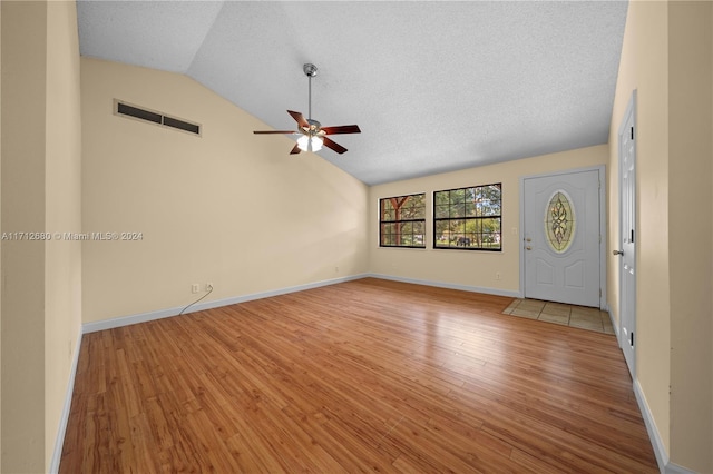 interior space featuring a textured ceiling, ceiling fan, light hardwood / wood-style floors, and vaulted ceiling