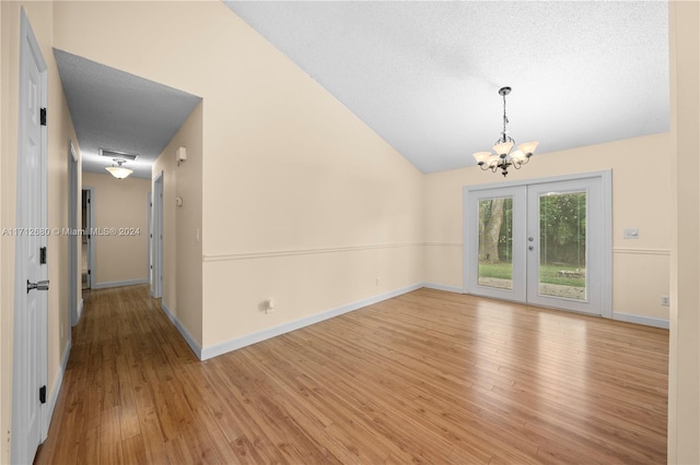 interior space featuring a chandelier, vaulted ceiling, a textured ceiling, and light hardwood / wood-style flooring