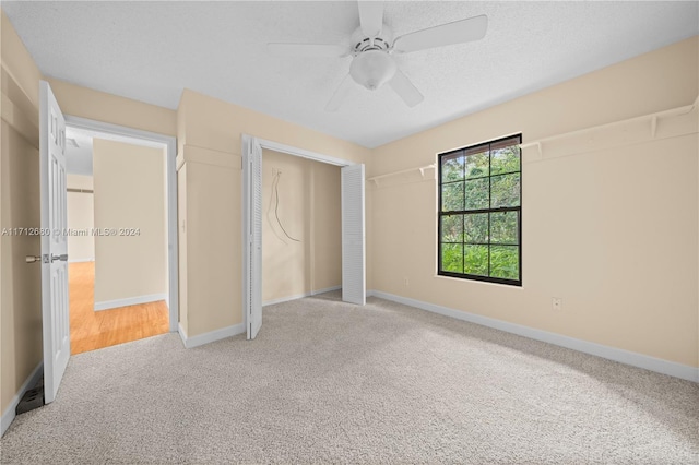 unfurnished bedroom featuring ceiling fan, a closet, light carpet, and a textured ceiling