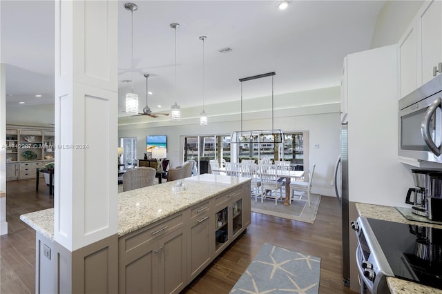 kitchen with pendant lighting, dark wood-type flooring, ceiling fan, appliances with stainless steel finishes, and white cabinetry