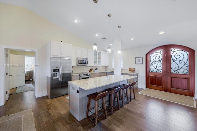 kitchen with white cabinetry, light stone countertops, a kitchen breakfast bar, decorative light fixtures, and appliances with stainless steel finishes