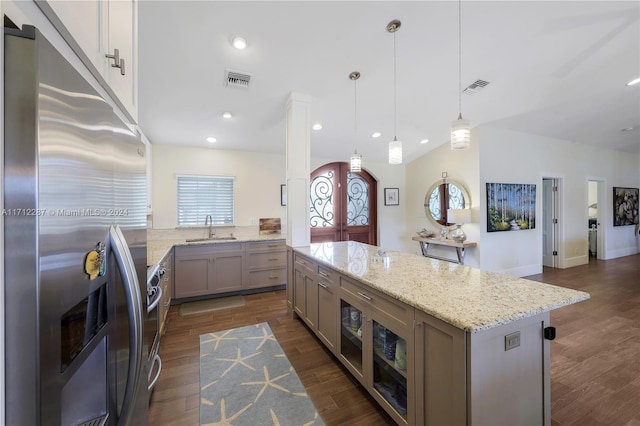 kitchen featuring sink, hanging light fixtures, light stone counters, dark hardwood / wood-style floors, and stainless steel refrigerator with ice dispenser