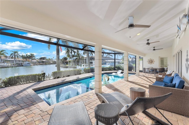 view of pool featuring glass enclosure, ceiling fan, a water view, and a patio