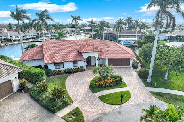 mediterranean / spanish-style house featuring a water view, a garage, and a front lawn