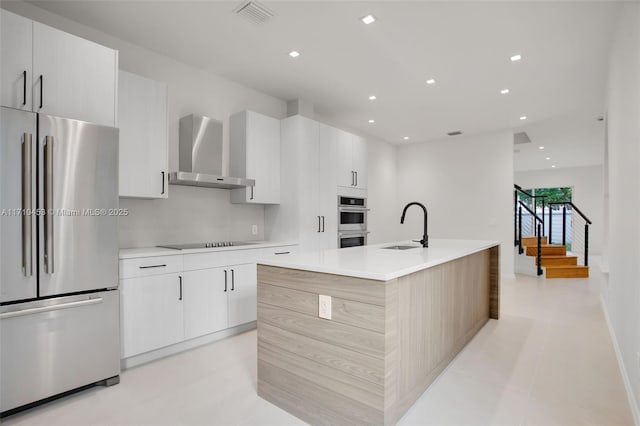 834 E Spinnaker Dr E, Hollywood, FL 33019 - kitchen featuring sink, a center island with sink, wall chimney range hood, stainless steel appliances, and white cabinets