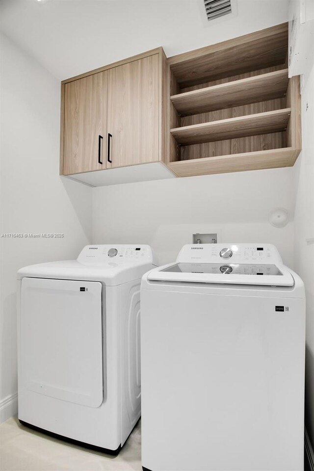 clothes washing area featuring cabinets and washer and dryer