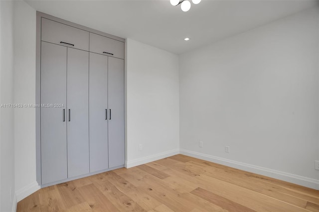 unfurnished bedroom with light hardwood / wood-style flooring and a closet