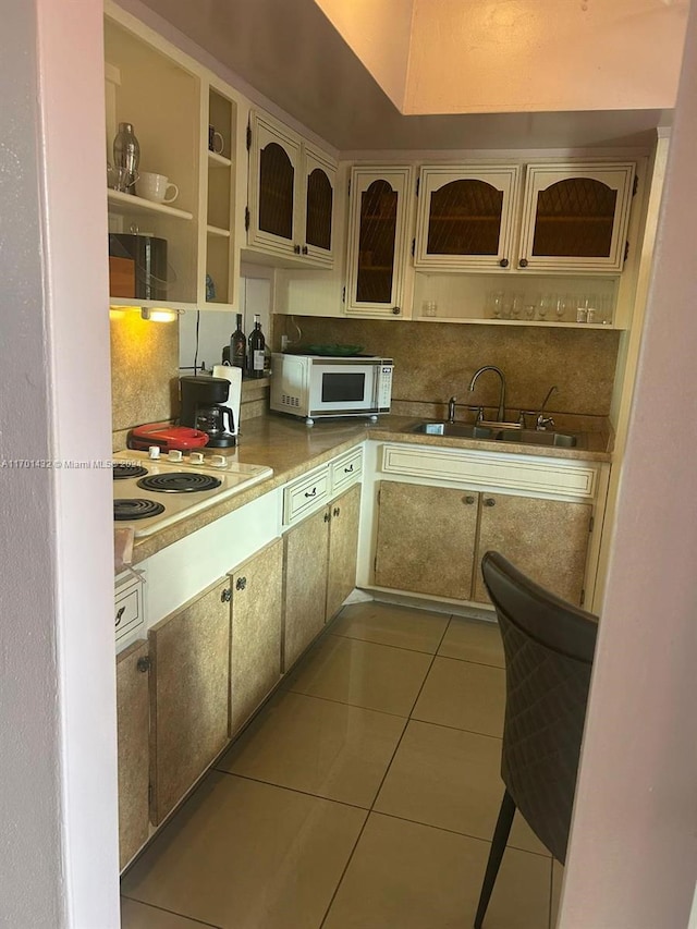 kitchen featuring light tile patterned flooring, cream cabinets, and sink