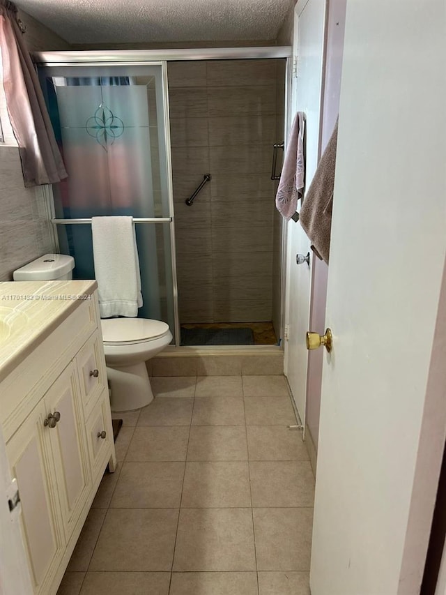 bathroom featuring tile patterned flooring, vanity, a textured ceiling, and walk in shower