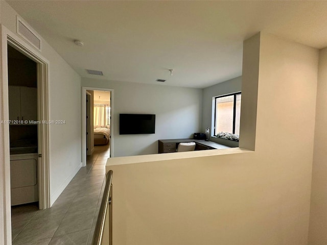 hallway with light tile patterned flooring and washer / dryer