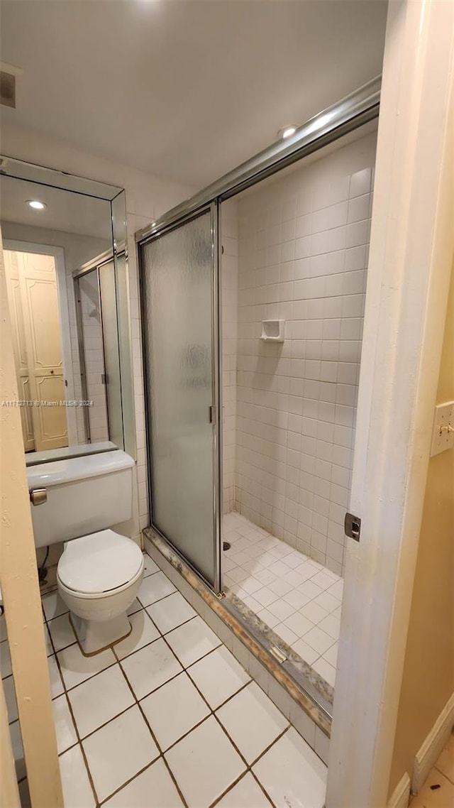 bathroom with tile patterned floors, toilet, and a shower with shower door