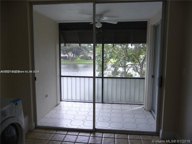 interior space featuring tile patterned floors, ceiling fan, a water view, and washer / dryer