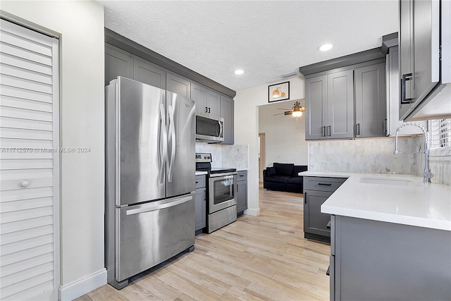 kitchen featuring appliances with stainless steel finishes, light hardwood / wood-style floors, gray cabinetry, and sink