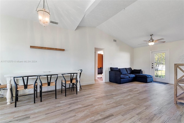 living room with a textured ceiling, ceiling fan with notable chandelier, lofted ceiling, and light wood-type flooring