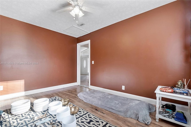 bedroom featuring hardwood / wood-style flooring, ceiling fan, and a textured ceiling