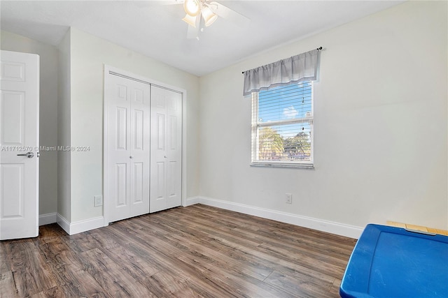 unfurnished bedroom featuring ceiling fan, a closet, and dark wood-type flooring