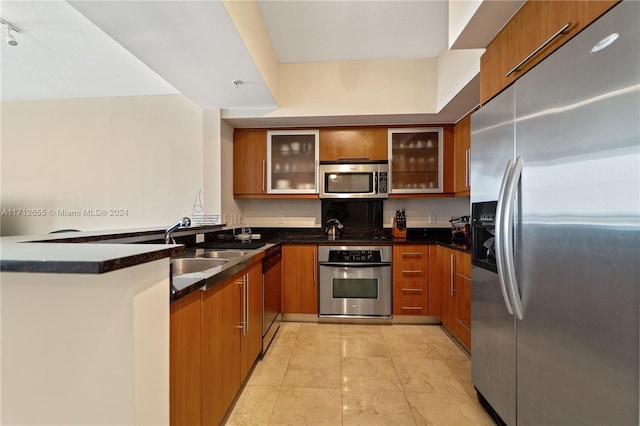 kitchen with sink, dark stone countertops, kitchen peninsula, and stainless steel appliances