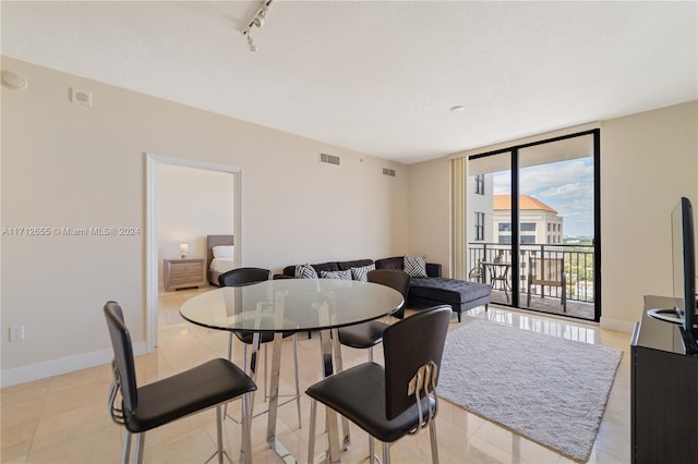 dining space with light tile patterned floors, track lighting, and expansive windows