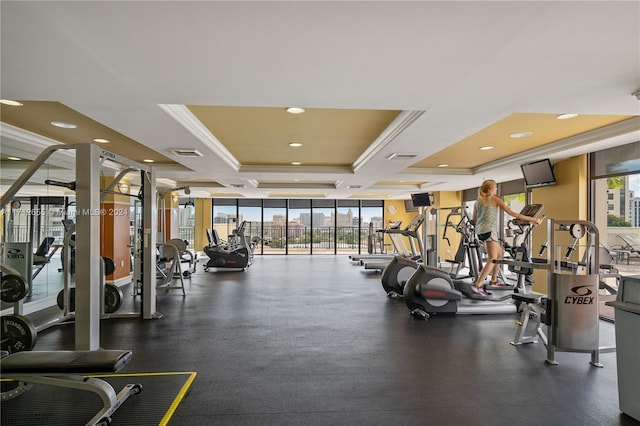 gym featuring a raised ceiling and crown molding