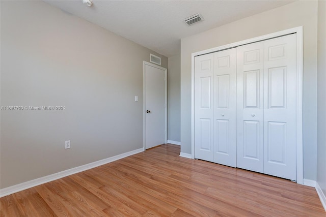 unfurnished bedroom with a closet and light wood-type flooring